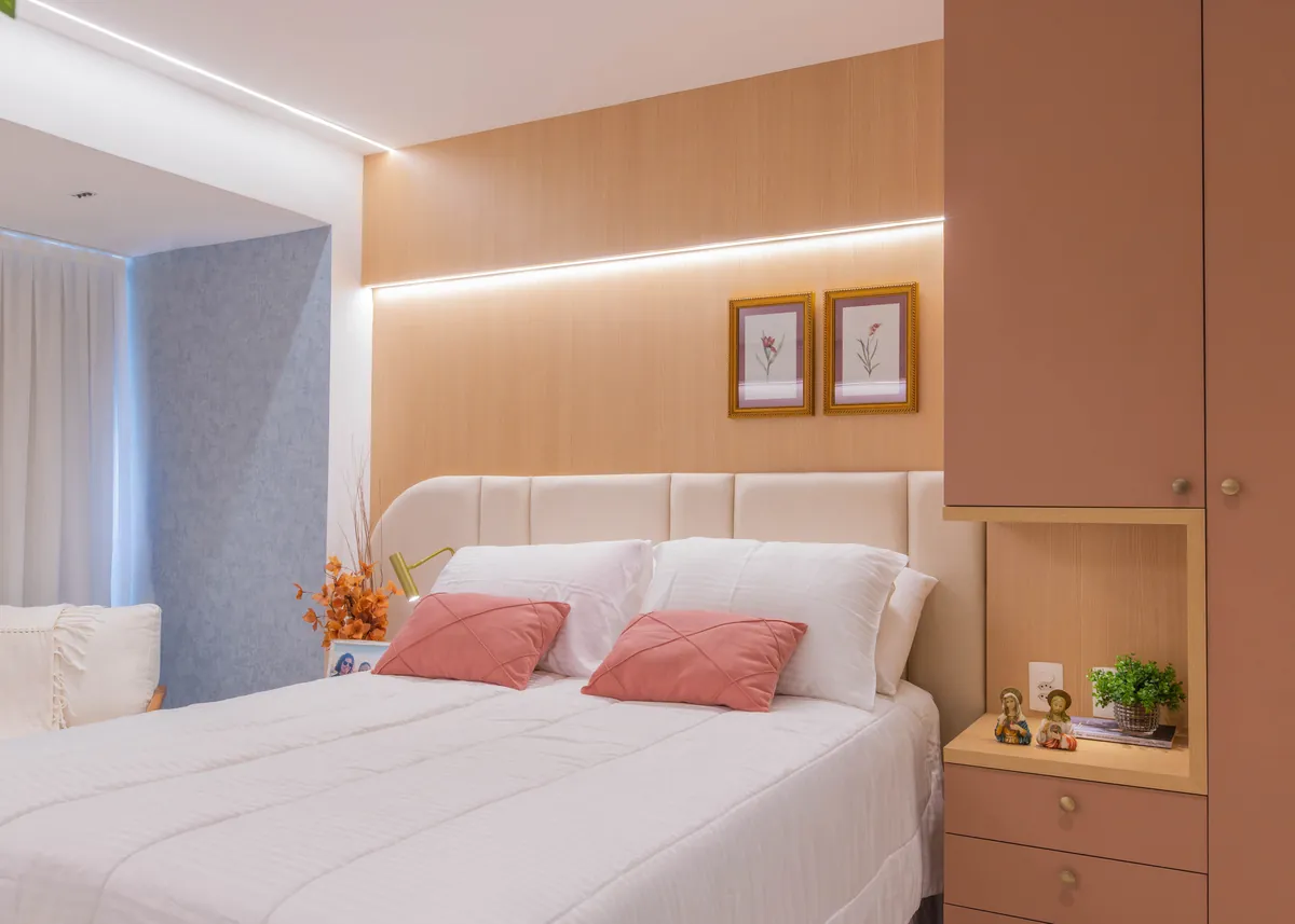 Quarto do Apartamento Blue: cabeceira estofada, painel de marcenaria rosé e luz indireta