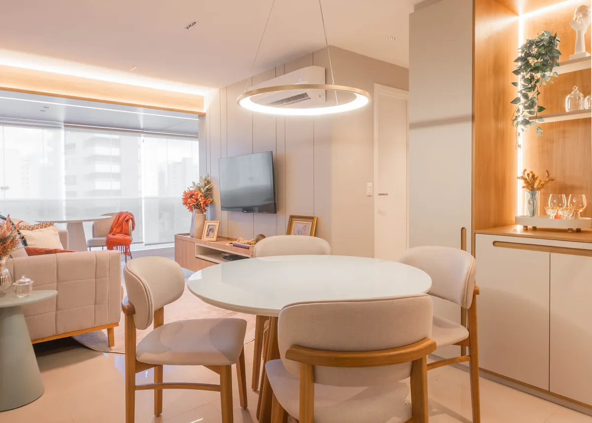 Estar e jantar do Apartamento Blue: sofá claro com manta verde, mesa redonda e painel de madeira