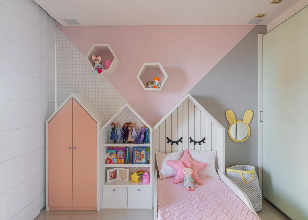 Quarto infantil em rosa e cinza, com cabeceira em formato de casinha e nichos hexagonais