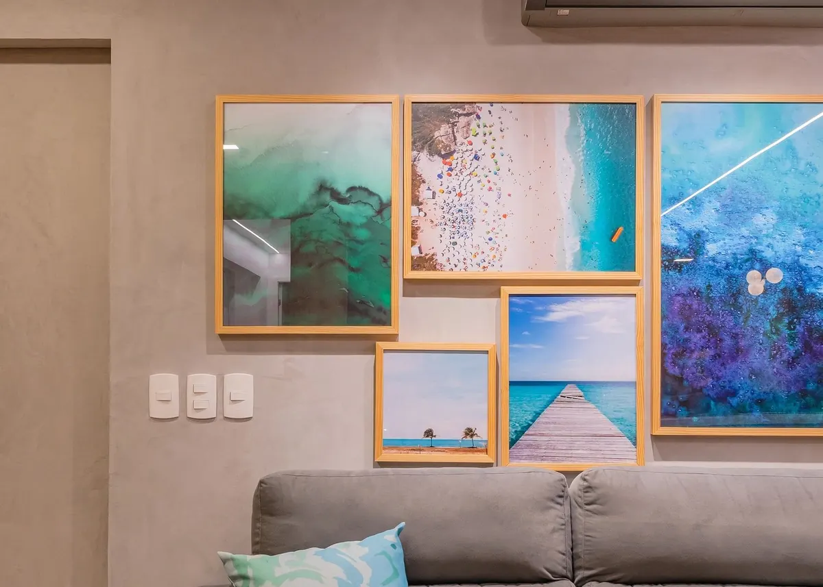 Parede de quadros em tons de azul sobre sofá claro