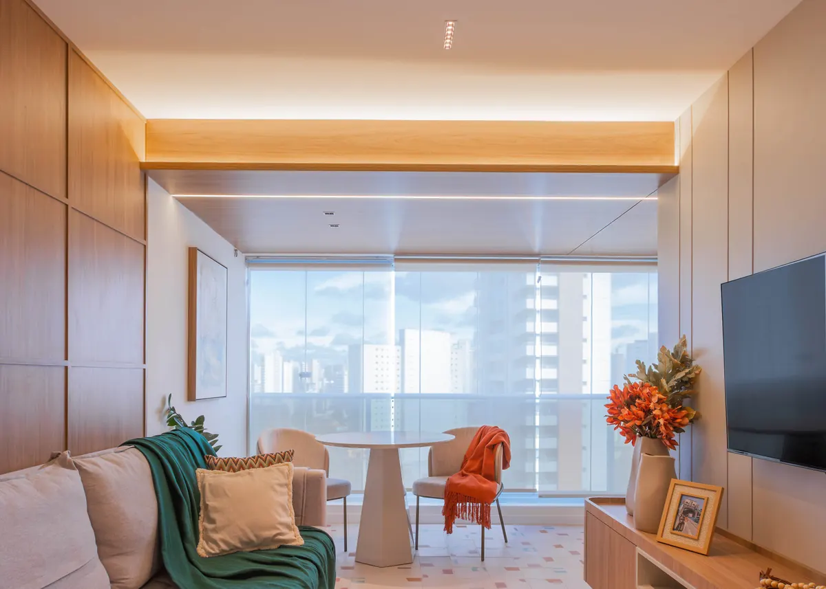 Sala de estar integrada à varanda, com marcenaria clara e vista para a cidade